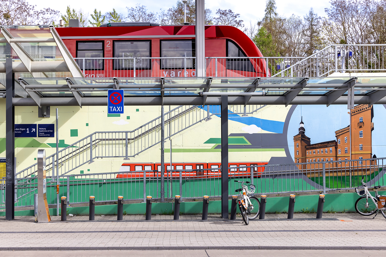 Die Station Erftstadt im Stadtteil Liblar. Man sieht das Kunstgraffiti. Auf dem Gleis steht eine vareo-Bahn.