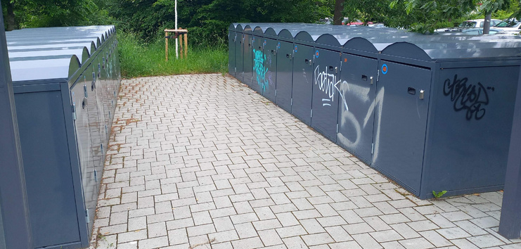 Die Radboxen an der Stations Troisdorf-Spich vor der Aktion "Streetart meets Stations". Die Boxen sind dunklegrau und mit Graffiti beschmiert.