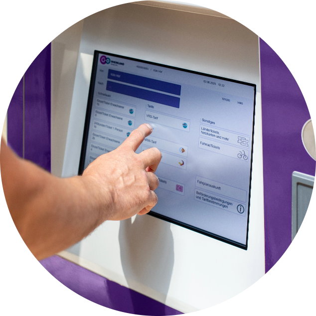 Die Hand einer Person berührt eine Touchscreen-Oberfläche auf einem Kiosk und wählt Optionen aus einem Menü aus. Auf dem Bildschirm werden verschiedene Serviceoptionen und Schaltflächen angezeigt, und der Kiosk ist teilweise lila und weiß.