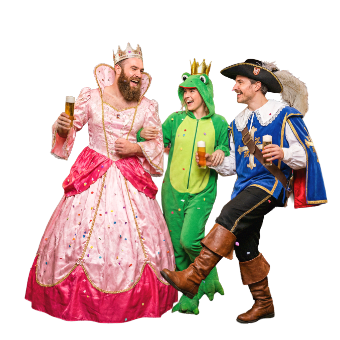 Drei Erwachsene in Kostümen - eine rosafarbene Prinzessin, ein grüner Frosch und ein Musketier - stehen lächelnd zusammen und halten Biergläser vor einem schlichten weißen Hintergrund.