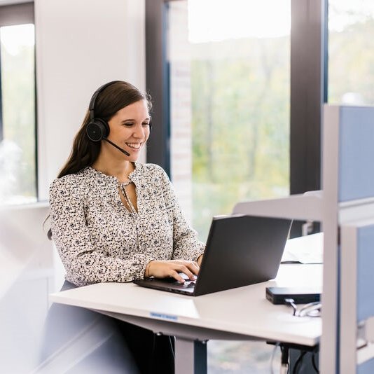 Mitarbeiterin beim Telefonieren am Laptop