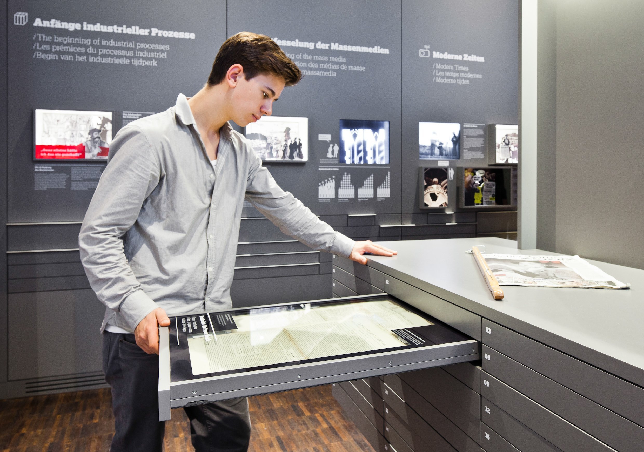 Ein Besucher des Internationalen Zeitungsmuseums liest sich die Inhalte einer Zeitungsschublade durch